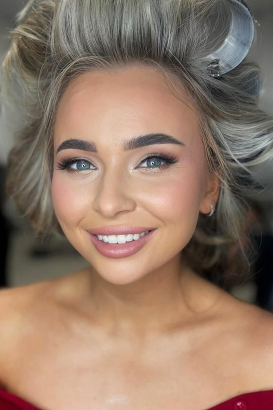 Girl smiling wearing hair rollers with natural glam makeup